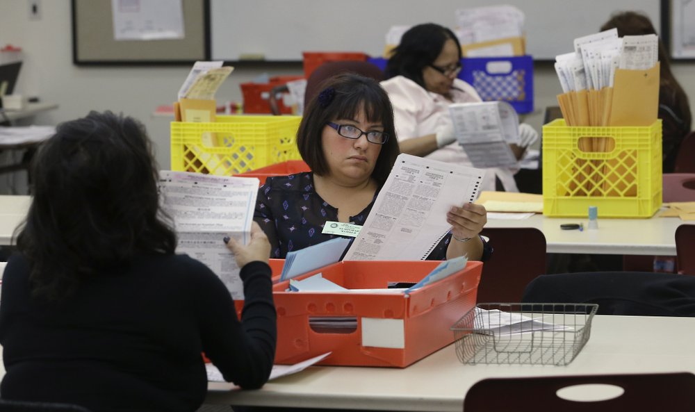 Temporary worker at the Sacramento Registrar of Voters, looks over a mail-in ballot 